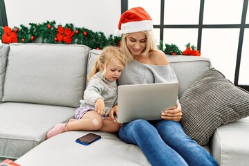 Poster - Mother and daughter using laptop sitting by christmas decor at home