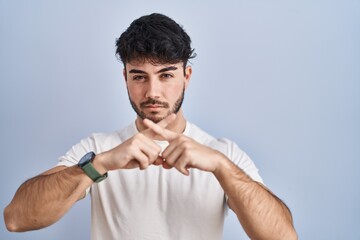 Sticker - Hispanic man with beard standing over white background rejection expression crossing fingers doing negative sign