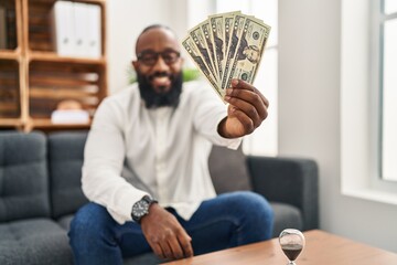 Wall Mural - Young african american man psychologist holding dollars at psychology center