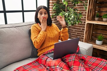 Sticker - Young hispanic woman using laptop holding virtual currency bitcoin covering mouth with hand, shocked and afraid for mistake. surprised expression