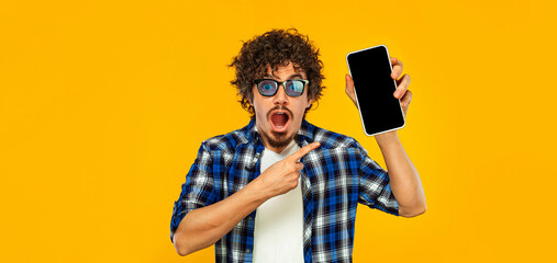 Idea for Mobile App Advertisement. Man Showing Smartphone Screen On Yellow Studio Background. Smiling Guy on Ads Template. Cellphone Display Mockup.