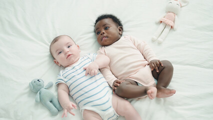 Two adorable babies lying on bed at bedroom