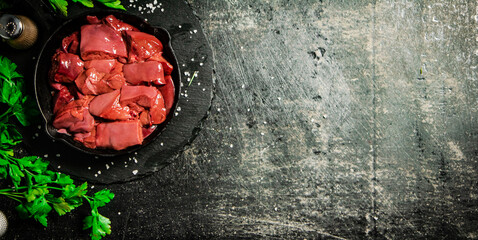 Poster - Pieces of raw liver in a frying pan with parsley and spices. 