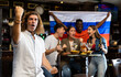 © JackF - Cheerful international sport football fans waving Russian flag and drinking beer, eating chips in the bar