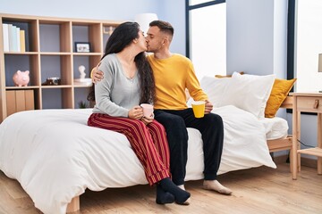 Poster - Man and woman couple drinking coffee sitting on bed at bedroom