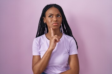 Sticker - African american woman with braids standing over pink background thinking concentrated about doubt with finger on chin and looking up wondering