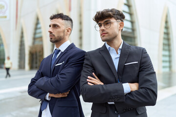 Wall Mural - Two hispanic men business workers standing with arms crossed gesture at street