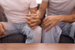 © Krakenimages.com - Two hispanic men couple sitting on sofa with hands together at home
