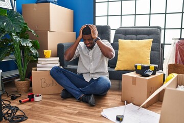 Wall Mural - African american man sitting on the floor at new home suffering from headache desperate and stressed because pain and migraine. hands on head.