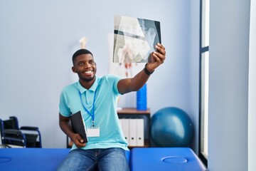 Canvas Print - Young african american man physiotherapist holding xray al rehab clinic