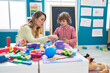 © Krakenimages.com - Teacher and toddler playing with geometry blocks sitting on table at kindergarten