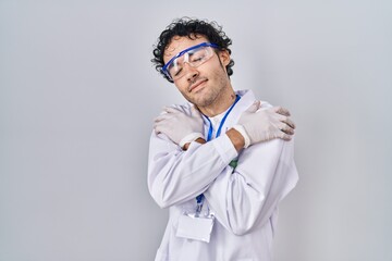 Wall Mural - Hispanic man working at scientist laboratory hugging oneself happy and positive, smiling confident. self love and self care