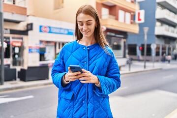 Canvas Print - Young caucasian woman smiling confident using smartphone at street