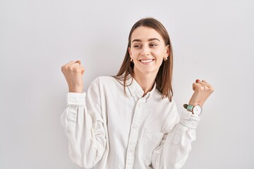 Canvas Print - Young caucasian woman standing over isolated background celebrating surprised and amazed for success with arms raised and eyes closed. winner concept.