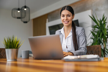 Female entrepreneur with laptop computer working at home office,looking at camera