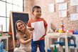 © Krakenimages.com - Teacher and toddler holding paper standing at kindergarten