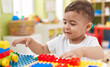 © Krakenimages.com - Adorable hispanic toddler playing with construction blocks sitting on table at kindergarten