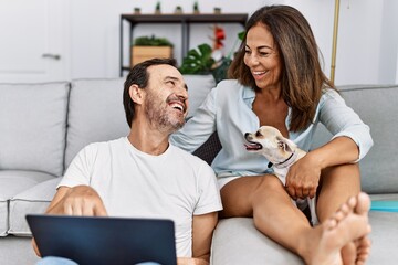 Wall Mural - Middle age man and woman couple using laptop sitting on sofa with chihuahua at home