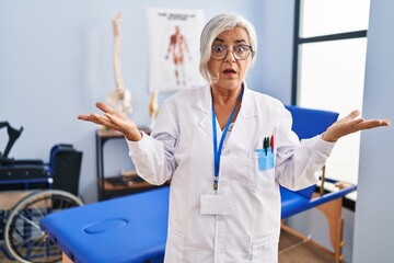 Sticker - Middle age woman with grey hair working at pain recovery clinic clueless and confused with open arms, no idea concept.