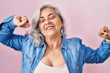 Wall Mural - Middle age woman with grey hair standing over pink background stretching back, tired and relaxed, sleepy and yawning for early morning