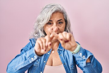 Canvas Print - Middle age woman with grey hair standing over pink background rejection expression crossing fingers doing negative sign