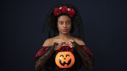 Sticker - African american woman wearing katrina costume holding halloween pumpkin basket over isolated black background