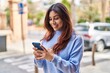 © Krakenimages.com - Young hispanic woman smiling confident using smartphone at street