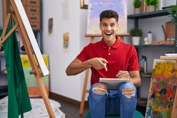 Sticker - Young hispanic man drawing on art notebook smiling happy pointing with hand and finger