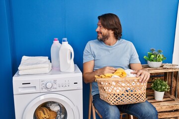 Poster - Handsome middle age man waiting for laundry looking to side, relax profile pose with natural face with confident smile.