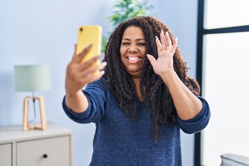 Poster - Plus size hispanic woman doing video call with smartphone looking positive and happy standing and smiling with a confident smile showing teeth