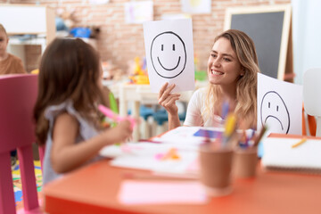 Wall Mural - Teacher and toddler sitting on table having emotion therapy at kindergarten