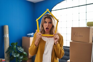 Poster - Young woman standing at new home in shock face, looking skeptical and sarcastic, surprised with open mouth