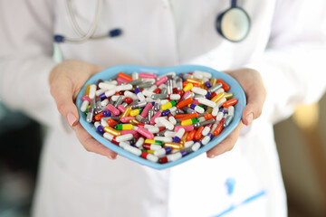 Wall Mural - Doctor with stethoscope holds pills in heart-shaped bowl.