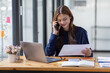 © David - Cheerful business Asian woman freelancer making telephone call share good news about project working in office workplace, business finance concept.
