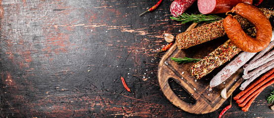 Canvas Print - Different types of salami sausage on a cutting board with rosemary. 