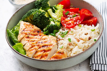 Wall Mural - Delicious buddha bowl with grilled chicken, fresh vegetables and rice on a light background.