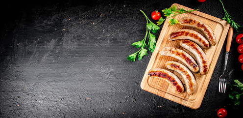 Canvas Print - Grilled sausages on a cutting board with tomatoes. 