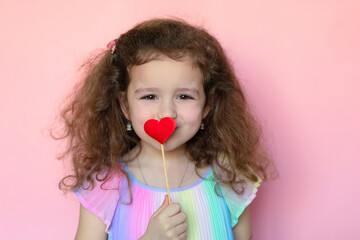 Portrait little cute girl send, blowing a kiss heart on pink background. creative child and valentines day. Love concept