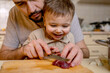 © Westend61 - Father cutting red meat with son in kitchen