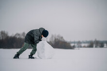 Boy Making A Snowman In Winter