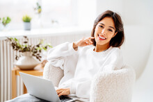 Happy Young Woman With Laptop Sitting On Chair