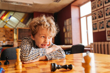 Boy Sitting At Table Playing Chess In Country Club