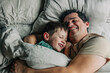 © Westend61 - Happy father and son lying on bed in bedroom