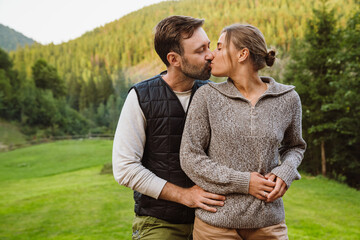 Wall Mural - White couple kissing and hugging together while walking in forest