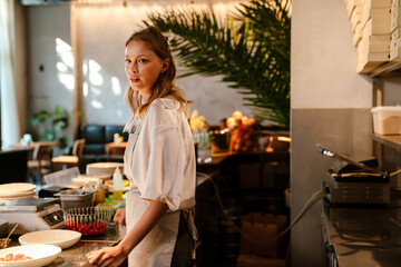 Young woman cooking meal while working in restaurant kitchen