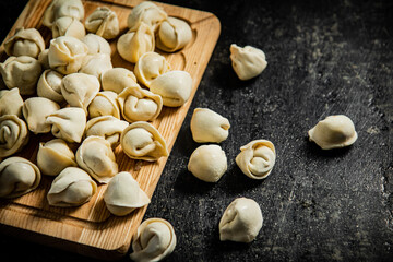 Poster - Raw homemade dumplings on a wooden cutting board. 