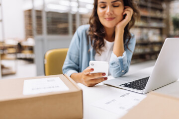 Wall Mural - Online store manager using a smartphone in a warehouse