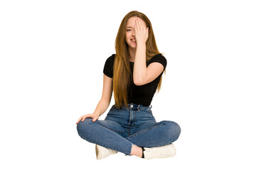 Wall Mural - Young redhead woman sitting on the floor cut out isolated having fun covering half of face with palm.