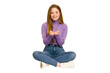 © Asier - Young redhead woman sitting on the floor cut out isolated holding something with both hands, product presentation.
