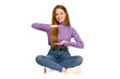 © Asier - Young redhead woman sitting on the floor cut out isolated holding something little with forefingers, smiling and confident.